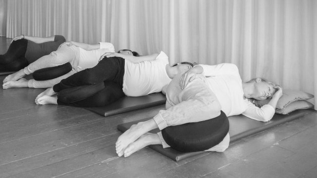 vier vrouwen liggen relaxed op hun zij bij de zwangerschapsyoga