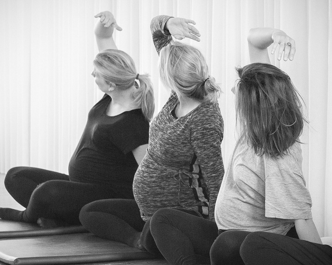 drie zwangere vrouwen doen yoga oefeningen bij de zwangerschapsyoga